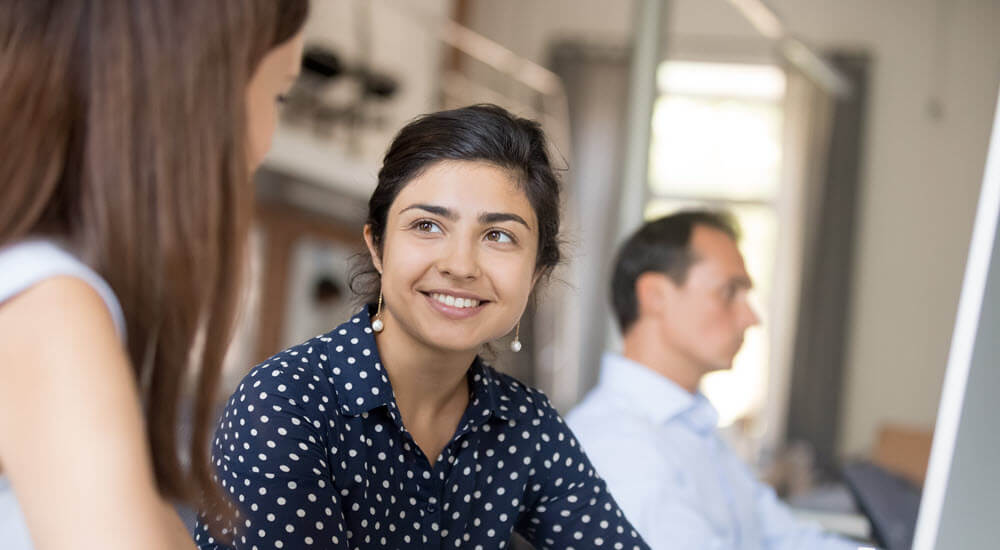 Colleagues communicating sitting in office at the desk